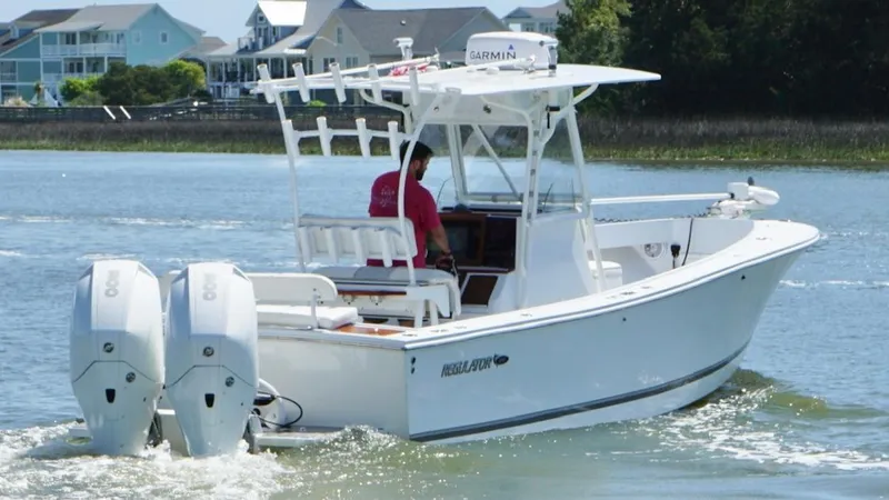 Slide: The Image of 2000 Regulator 26 Classic boat with dual engines cruising on a scenic waterway. - 9