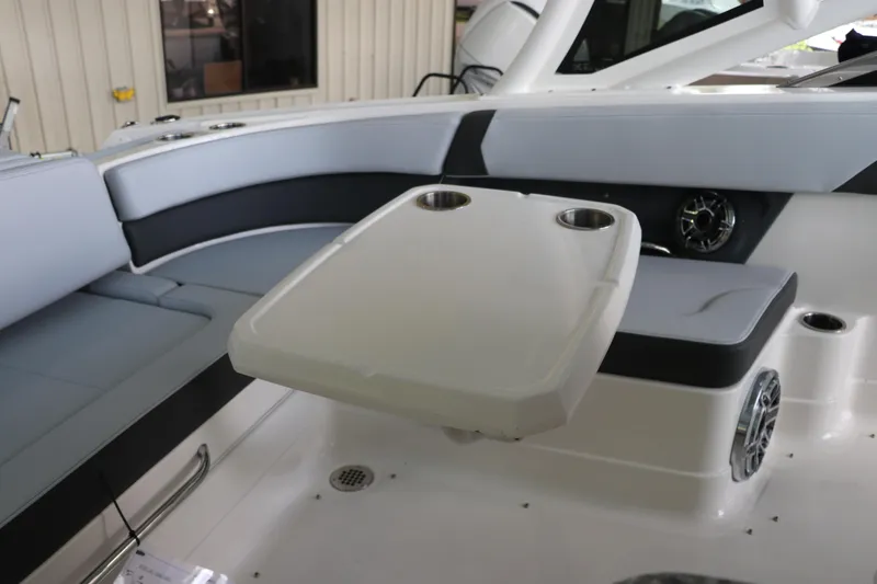 Slide: The Image of 2025 Chaparral 280 OSX boat interior with seating and table, featuring cup holders. - 18