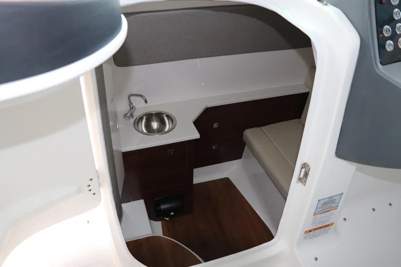 Slide: The Image of 2025 Chaparral 280 OSX cabin interior with sink, seating, and wood accents. - 35