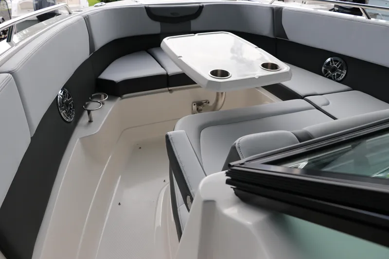 Slide: The Image of 2025 Chaparral 280 OSX boat interior with seating and table, featuring cup holders and speakers. - 42