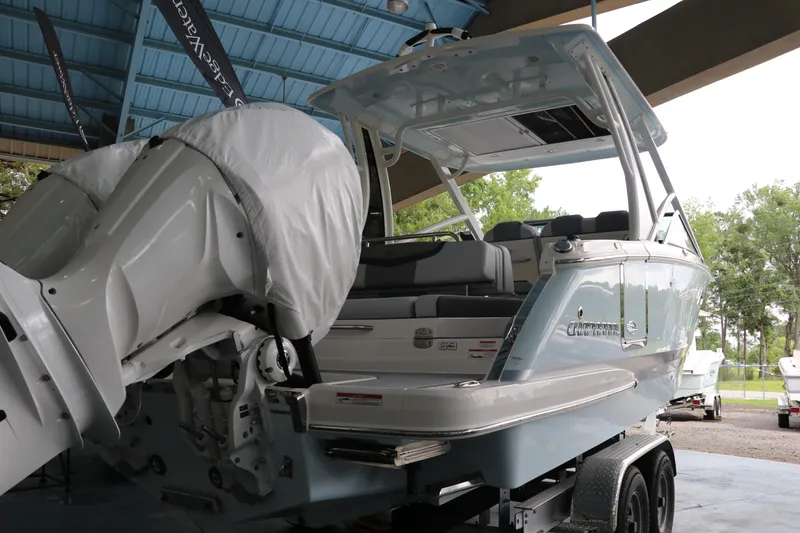 Slide: The Image of 2025 Chaparral 280 OSX boat with covered engines, displayed under a blue roof. - 5