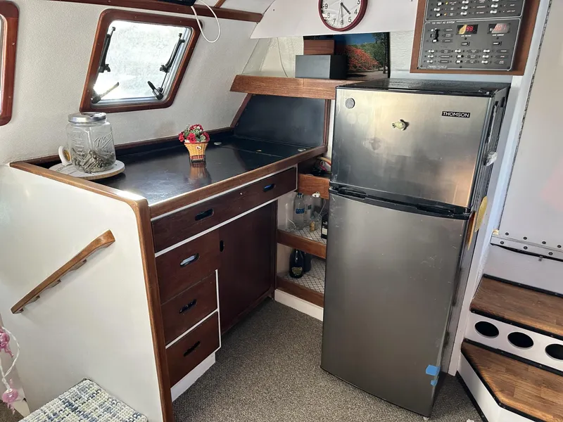 Slide: The Image of 1972 Custom 53 Catamaran interior with kitchenette, fridge, and wooden cabinetry. - 11