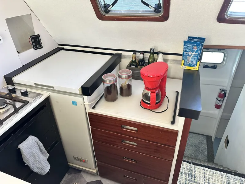 Slide: The Image of 1972 Custom 53 Catamaran kitchen with coffee maker, fridge, and storage drawers. - 14