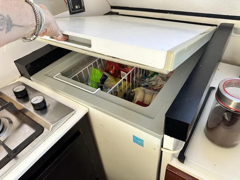 Slide: The Image of Opening a freezer on a 1972 Custom 53 Catamaran, next to a stove and jar. - 16
