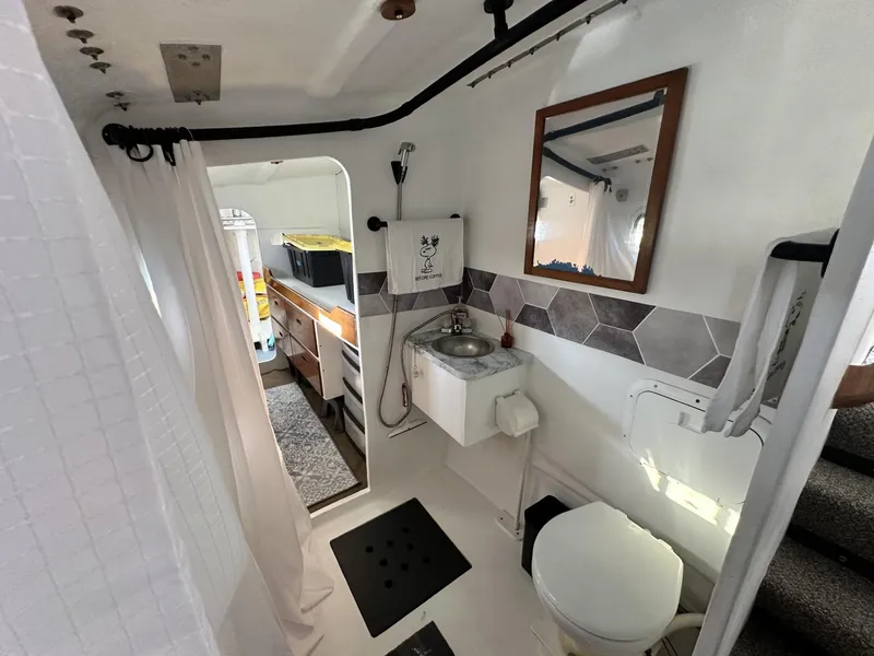 Slide: The Image of 1972 Custom 53 Catamaran bathroom with sink, toilet, and mirror, featuring hexagonal tile accents. - 24