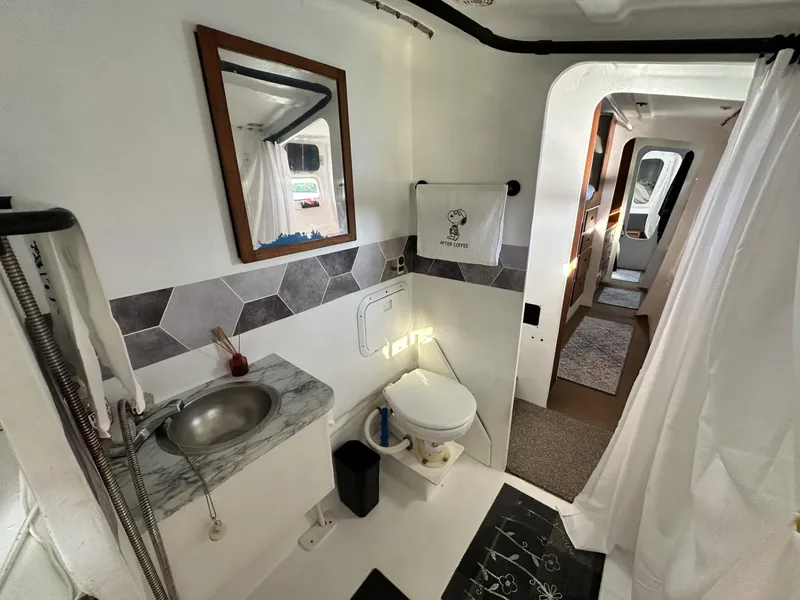 Slide: The Image of Interior of a 1972 Custom 53 Catamaran bathroom with modern fixtures and hexagonal tile accents. - 25