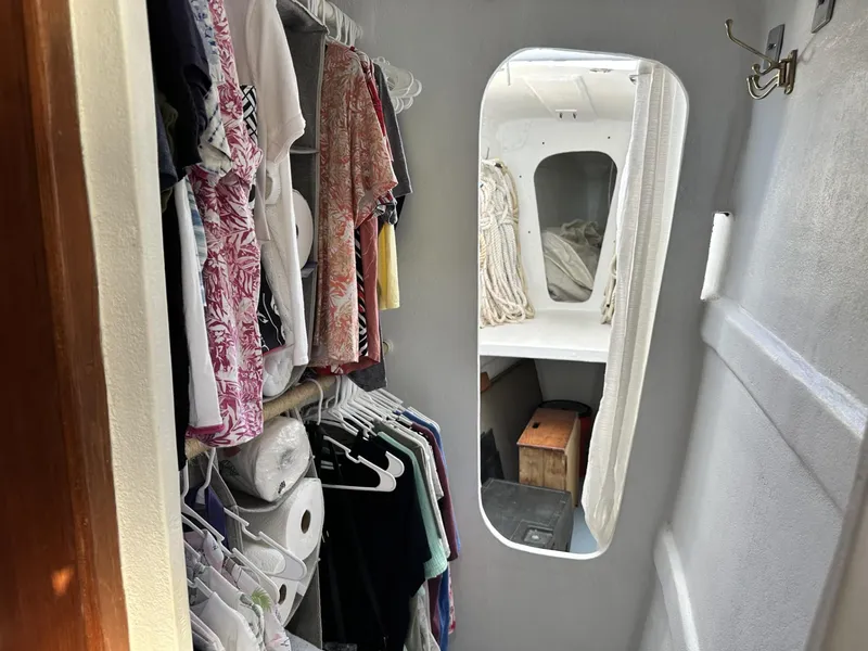 Slide: The Image of Interior of a 1972 Custom 53 Catamaran with clothes hanging in a narrow passageway. - 27