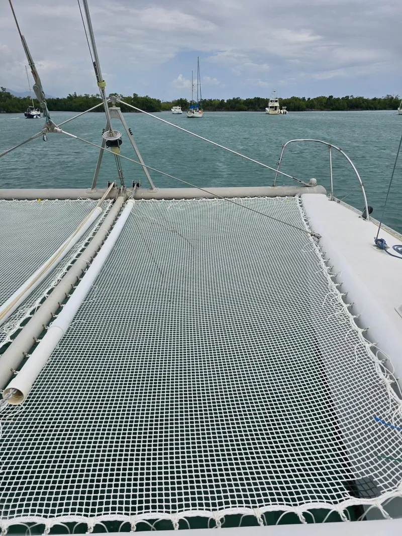 Slide: The Image of 1972 Custom 53 Catamaran with netting, anchored in calm waters under cloudy skies. - 42