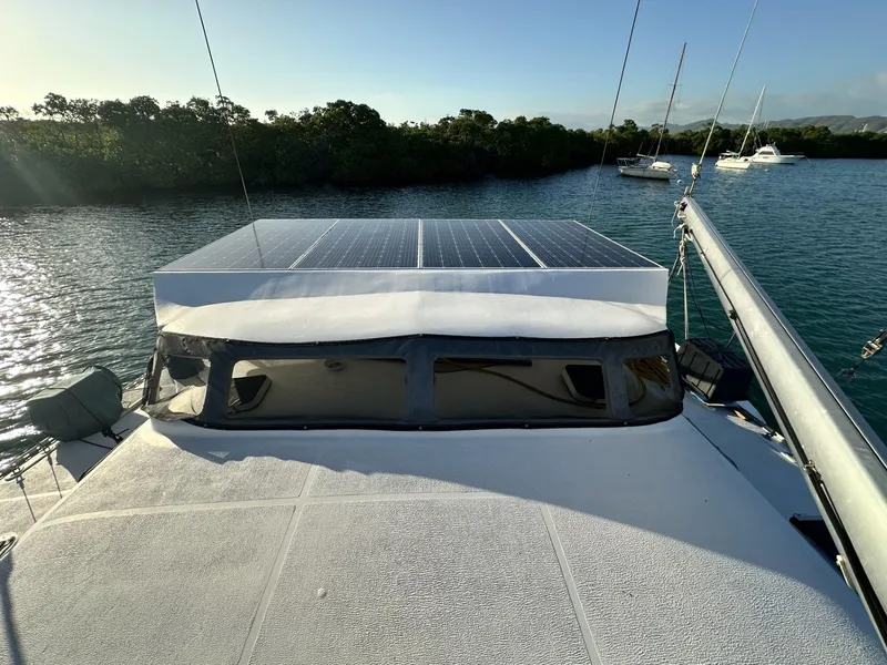 Slide: The Image of 1972 Custom 53 Catamaran with solar panels, anchored in a serene bay. - 43