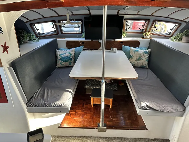 Slide: The Image of Interior of a 1972 Custom 53 Catamaran with cozy seating and a central table. - 7
