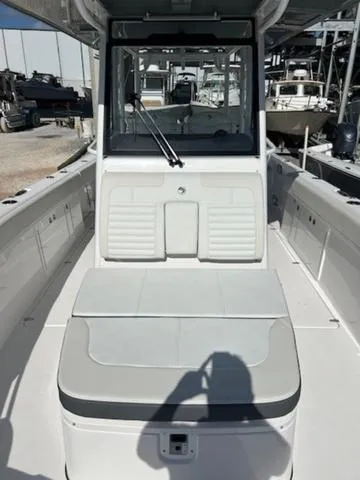 Slide: The Image of 2024 Edgewater 340CC boat interior with seating and console, docked in a marina. - 11