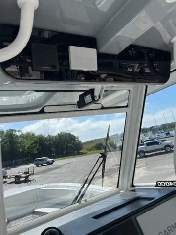 Slide: The Image of 2024 Edgewater 340CC boat interior with windshield and electronics, parked at marina. - 18