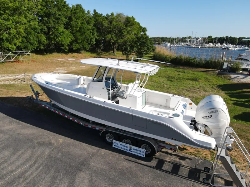 Slide: The Image of 2024 Edgewater 340CC boat on trailer near marina, surrounded by greenery. - 2