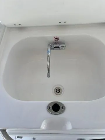 Slide: The Image of 2024 Edgewater 340CC boat sink with chrome faucet and drain. - 20