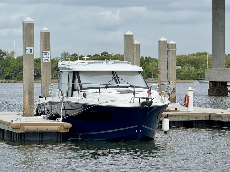 Slide: The Image of 2022 Jeanneau NC 1095 Coupe docked at a marina under cloudy skies. - 0