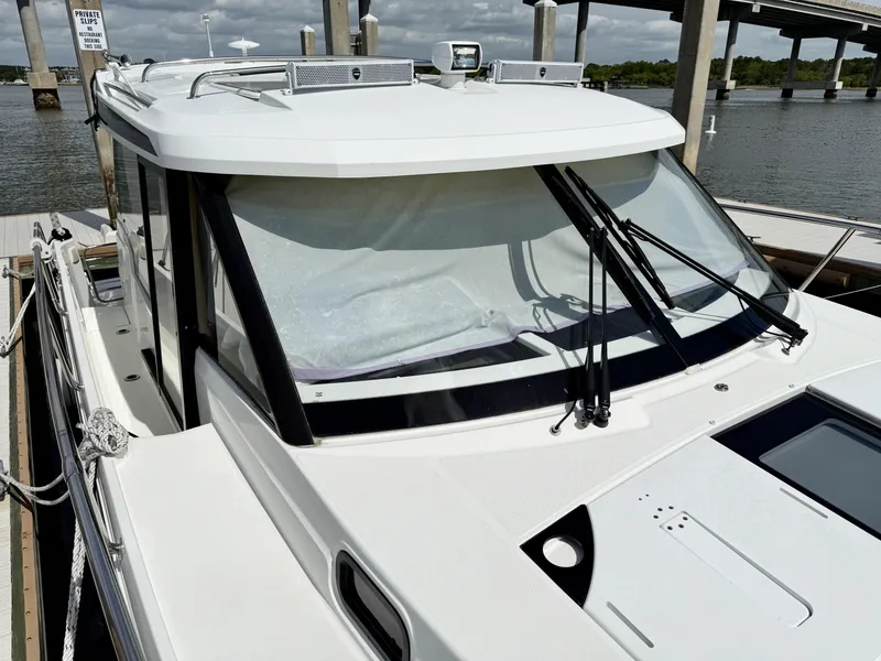 Slide: The Image of 2022 Jeanneau NC 1095 Coupe boat docked, showcasing sleek design and modern features. - 10