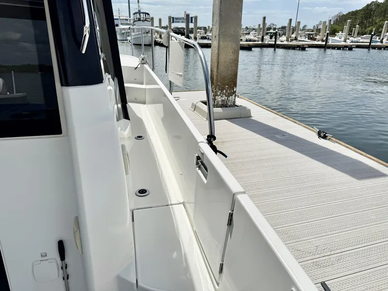 Slide: The Image of 2022 Jeanneau NC 1095 Coupe docked at marina, showcasing sleek side deck design. - 11