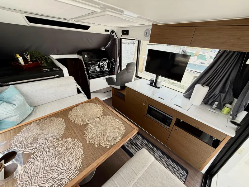 Slide: The Image of Interior of 2022 Jeanneau NC 1095 Coupe with modern seating, table, and entertainment system. - 14