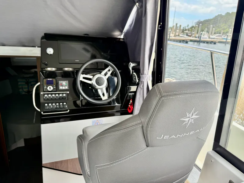 Slide: The Image of 2022 Jeanneau NC 1095 Coupe helm with steering wheel and control panel, dockside view. - 18