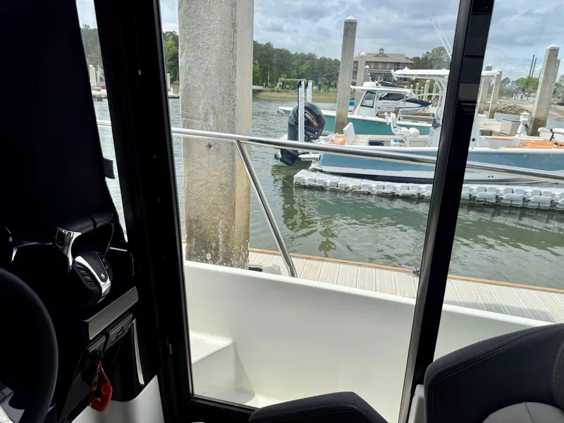 Slide: The Image of 2022 Jeanneau NC 1095 Coupe interior view, docked at marina with boats in background. - 19