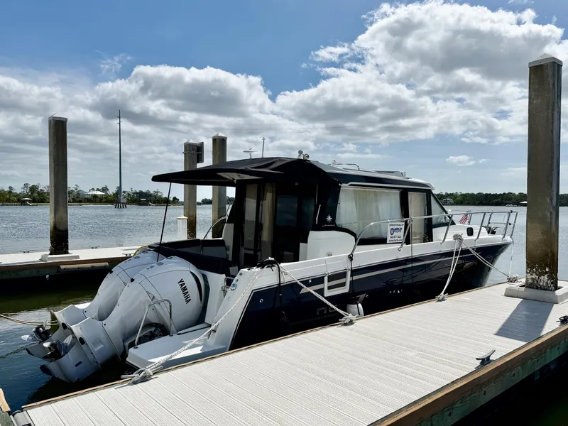 Slide: The Image of 2022 Jeanneau NC 1095 Coupe docked at marina under cloudy sky. - 2