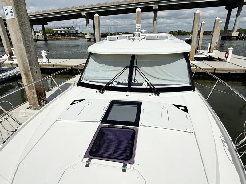 Slide: The Image of 2022 Jeanneau NC 1095 Coupe docked near a bridge, showcasing sleek design and spacious deck. - 9