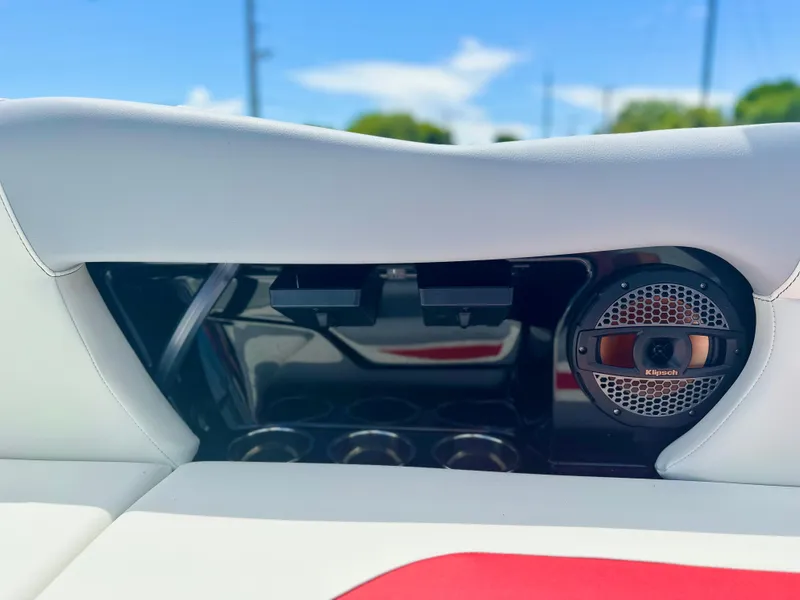 Slide: The Image of 2023 MasterCraft NXT24 boat interior with speaker and cup holders, under clear blue sky. - 14