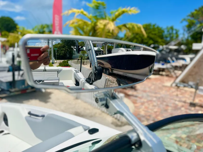 Slide: The Image of 2023 MasterCraft NXT24 boat mirror reflecting outdoor scene with palm trees and clear sky. - 35