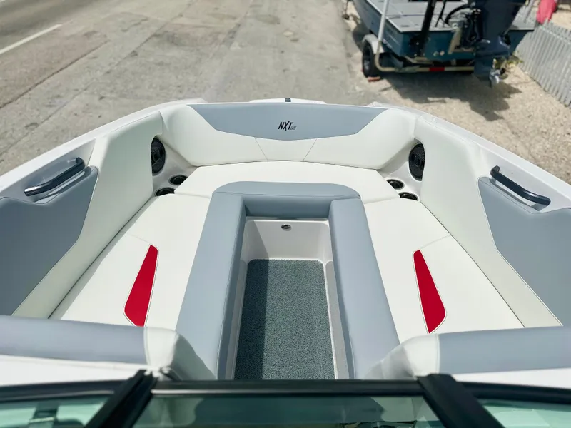Slide: The Image of 2023 MasterCraft NXT24 boat interior with white and red seating, gray flooring. - 37