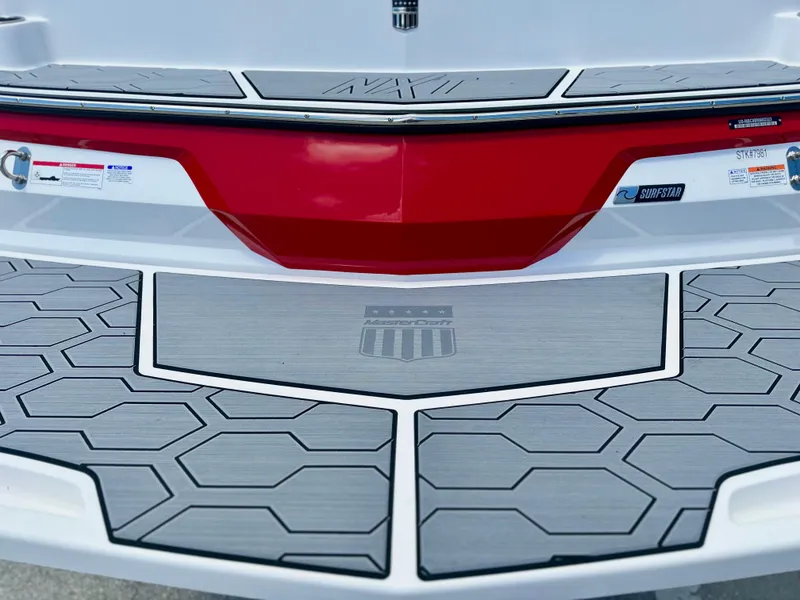 Slide: The Image of 2023 MasterCraft NXT24 boat stern with red and gray detailing, featuring non-slip decking. - 5