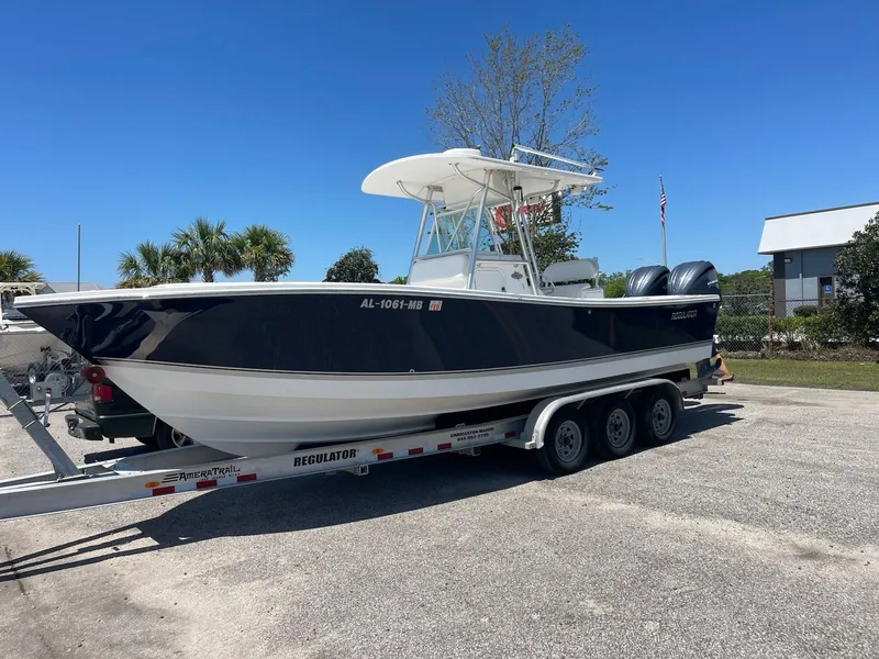 Slide: The Image of 2007 Regulator 26 Forward Seating boat on trailer, parked outdoors under clear blue sky. - 2