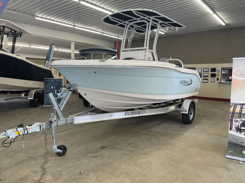 The Image of 2025 Robalo R180 Center Console boat displayed indoors on a trailer. - 0