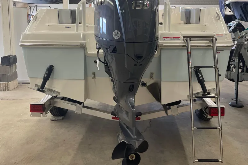 Slide: The Image of 2025 Robalo R180 Center Console boat with outboard motor and ladder in a showroom. - 16