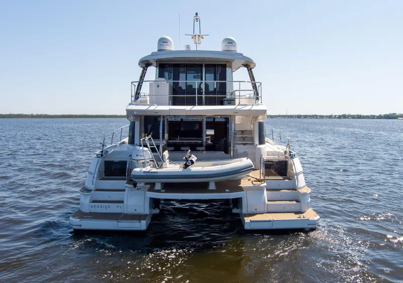 Slide: The Image of Aquila 54 Yacht 2022 on open water, rear view showcasing deck and tender. - 2