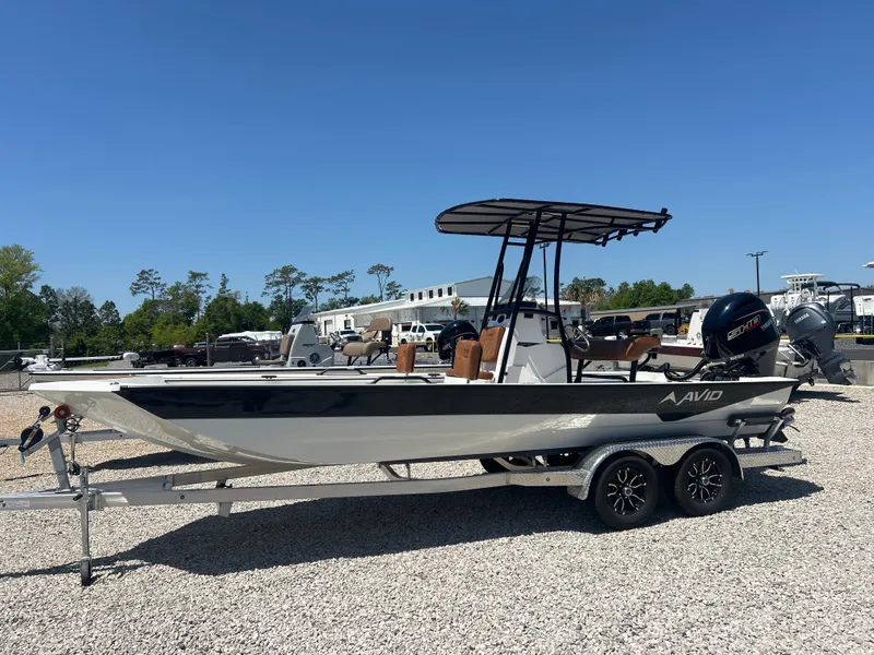 Slide: The Image of 2025 Avid 22 Recon boat on trailer, parked outdoors under clear blue sky. - 1
