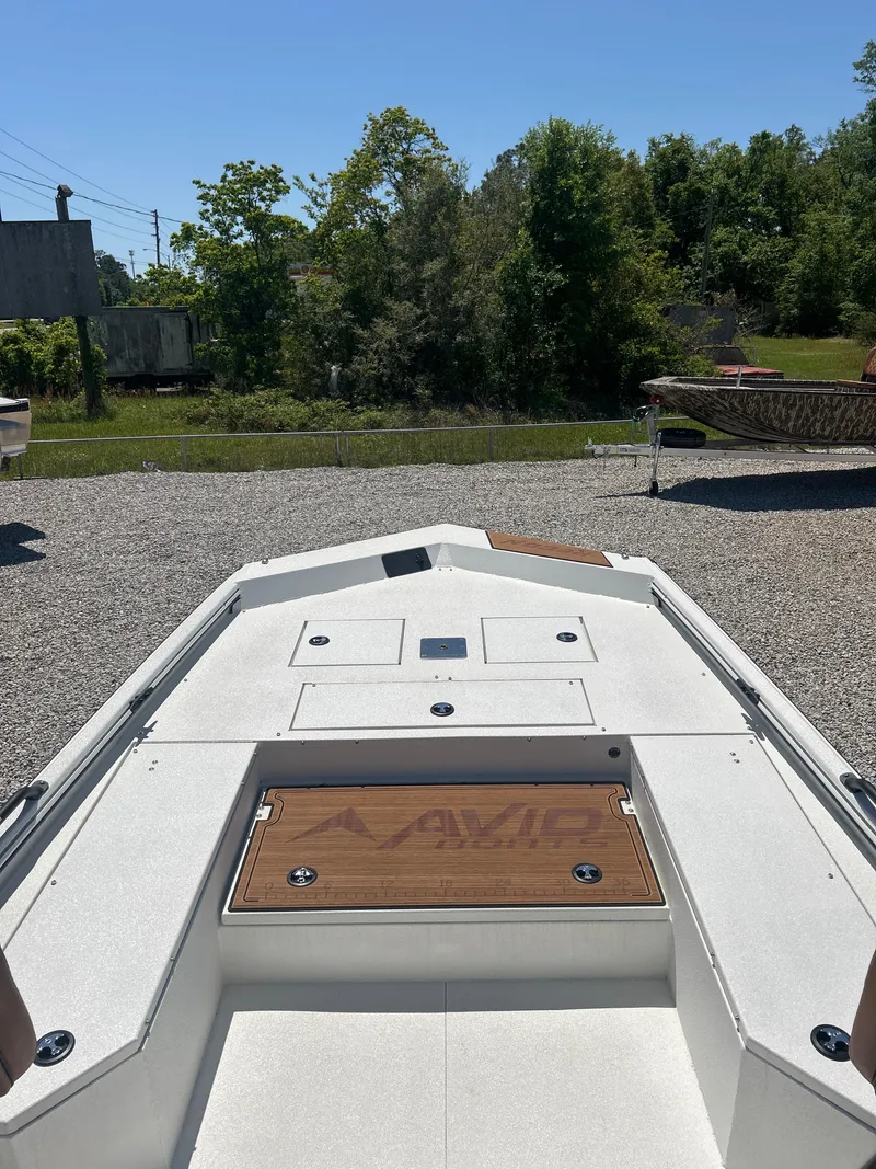 Slide: The Image of 2025 Avid 22 Recon boat on gravel, surrounded by greenery and clear blue sky. - 12