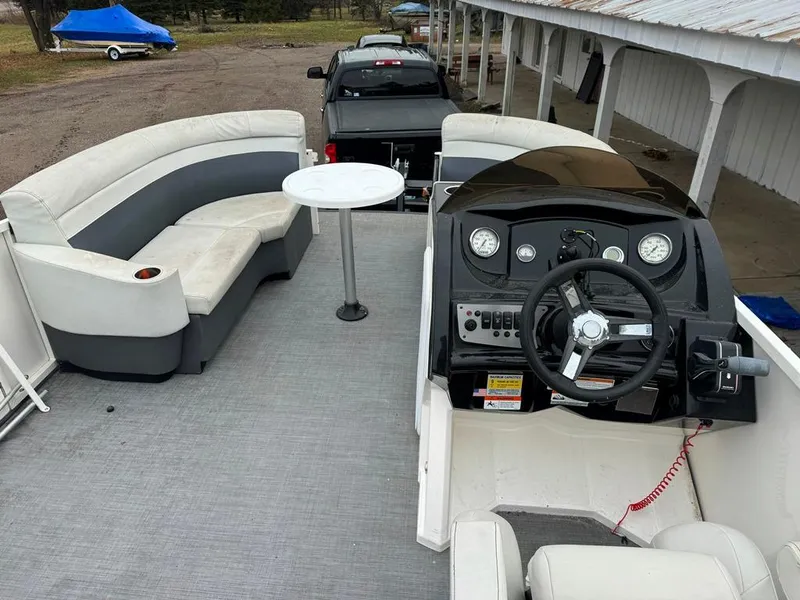 Slide: The Image of 2017 Larson Escape Cruze boat interior with seating, table, and steering console. - 1