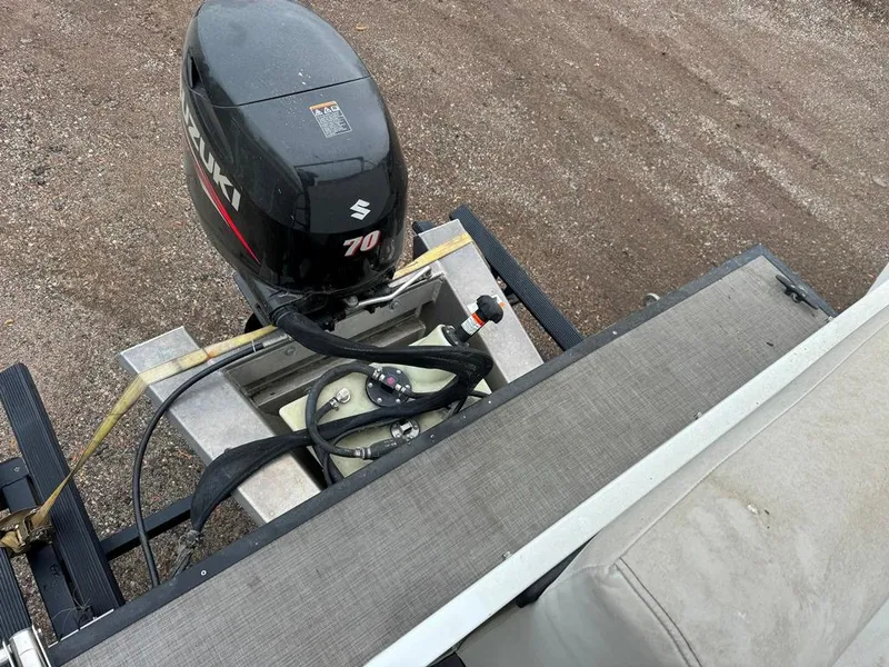 Slide: The Image of Outboard motor on a 2017 Larson Escape Cruze boat, parked on gravel. - 2