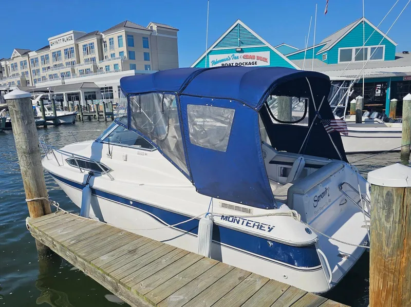 Slide: The Image of 1995 Monterey 246 SEL cruiser docked at marina with blue canopy and nearby buildings. - 2
