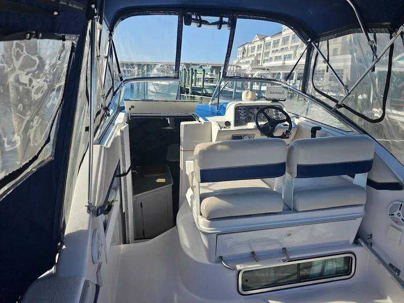 Slide: The Image of 1995 Monterey 246 SEL cruiser interior with helm, seating, and marina view. - 4