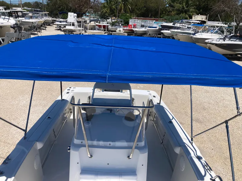 Slide: The Image of 2007 Edgewater 205CC boat with blue canopy, docked among other boats. - 11