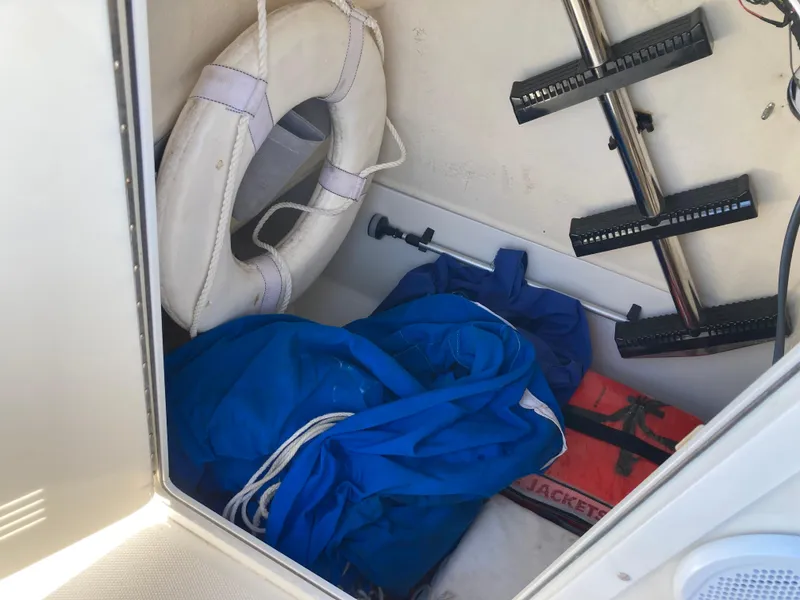 Slide: The Image of Storage compartment of 2007 Edgewater 205CC boat with life jacket, life ring, and blue tarp. - 16