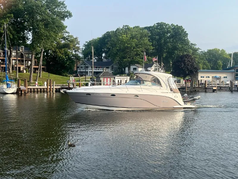 Slide: The Image of 2008 Rinker 400 Express Cruiser on a calm river near docks and lush greenery. - 0