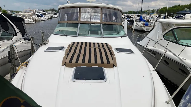 Slide: The Image of 2008 Rinker 400 Express Cruiser docked at marina, featuring spacious deck and striped sun pad. - 1