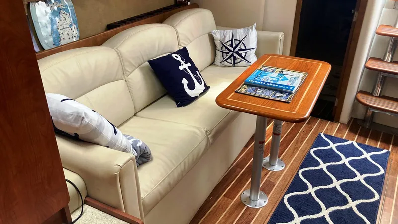 Slide: The Image of 2008 Rinker 400 Express Cruiser interior with beige sofa, nautical pillows, and wooden table. - 15
