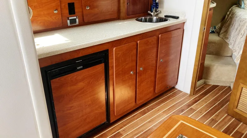 Slide: The Image of 2008 Rinker 400 Express Cruiser interior with wood cabinets and compact kitchenette. - 17