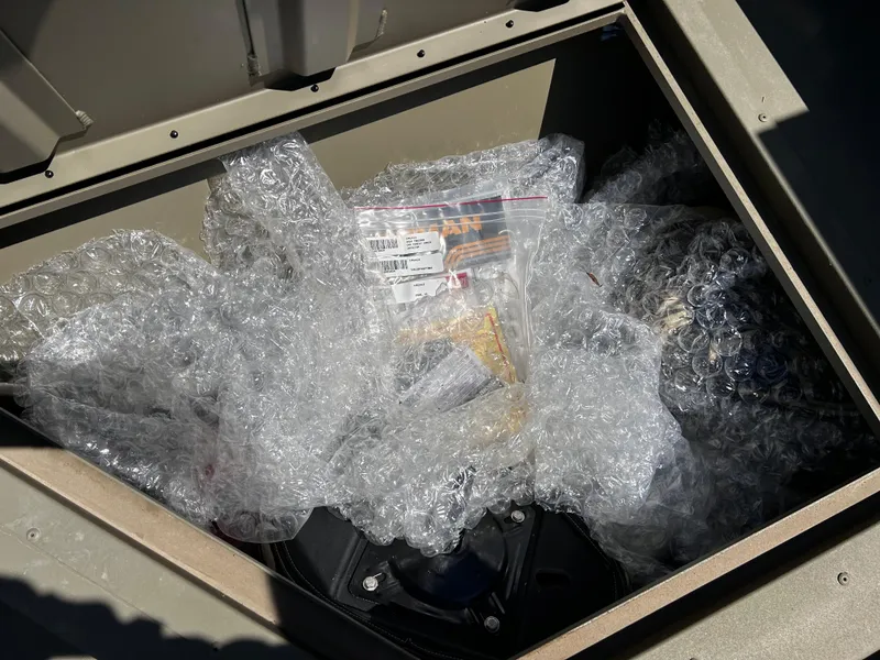 Slide: The Image of Storage compartment of 2024 Tracker Grizzly 2072 CC Sportsman with bubble wrap and documents. - 16