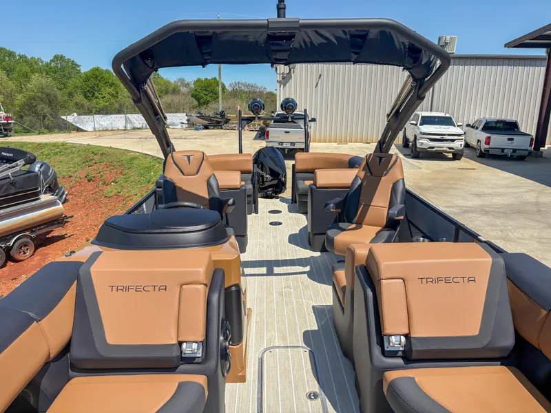 Slide: The Image of Luxurious 2025 Trifecta 25 RF SS pontoon boat with tan and black seating, docked outdoors. - 15