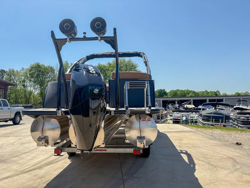 Slide: The Image of 2025 Trifecta 25 RF SS pontoon boat with dual engines, parked outdoors on a sunny day. - 2