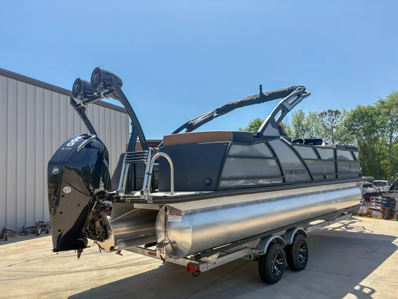 Slide: The Image of 2025 Trifecta 25 RF SS pontoon boat on trailer, parked outdoors. - 3